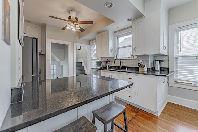 kitchen with stainless steel appliances, sink, white cabinets, and a breakfast bar