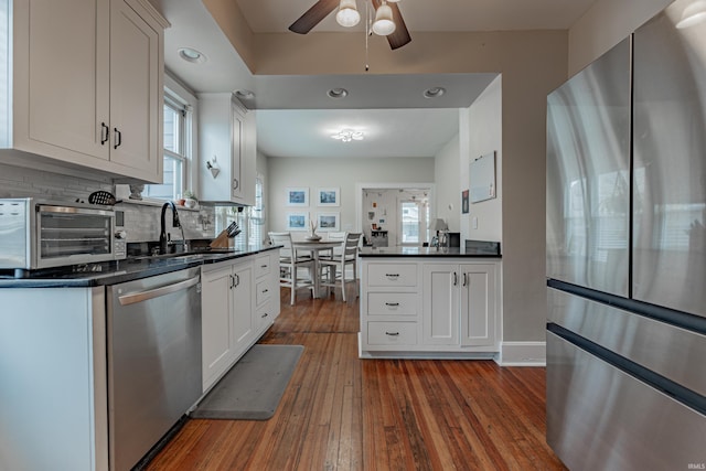 kitchen featuring sink, dark wood-type flooring, white cabinetry, stainless steel appliances, and tasteful backsplash