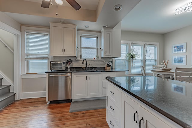 kitchen featuring stainless steel dishwasher, light hardwood / wood-style floors, sink, and white cabinets