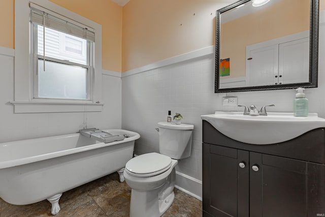 bathroom with a bathing tub, tile walls, vanity, and toilet