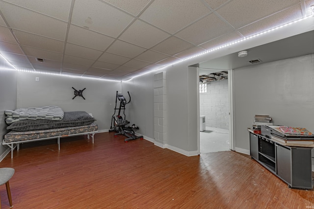 bedroom featuring a drop ceiling, wood-type flooring, and ensuite bathroom