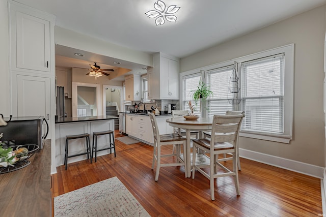 dining room featuring hardwood / wood-style floors, sink, and ceiling fan