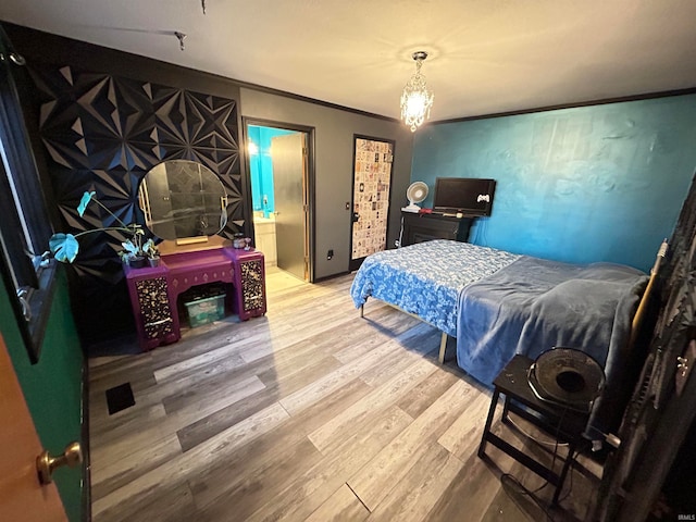 bedroom with hardwood / wood-style floors, ornamental molding, and ensuite bath