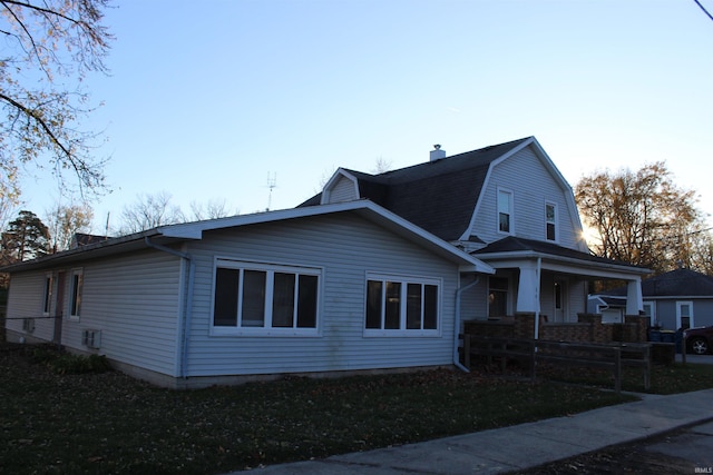 view of side of home featuring a yard and covered porch