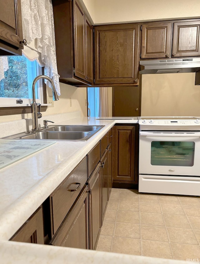 kitchen featuring white range oven, sink, and light tile patterned flooring