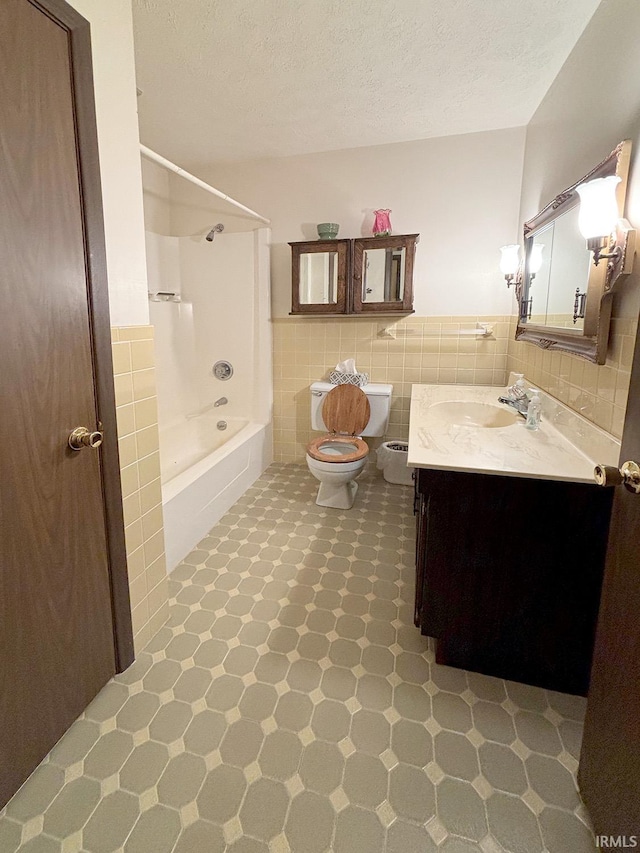 full bathroom with shower / bath combination, toilet, tile walls, a textured ceiling, and vanity