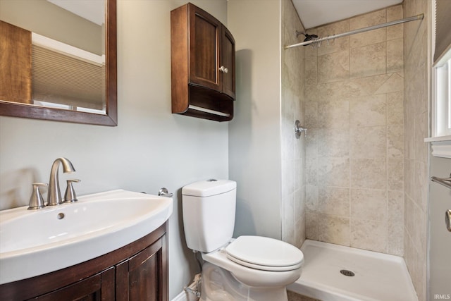 bathroom with a tile shower, vanity, and toilet