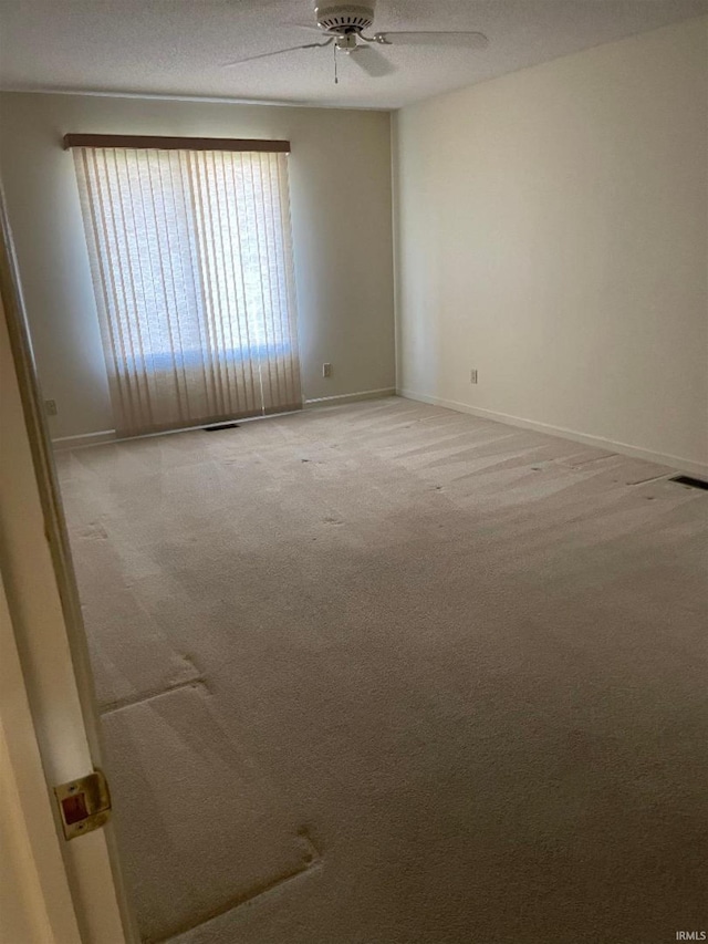 carpeted empty room featuring ceiling fan and a textured ceiling