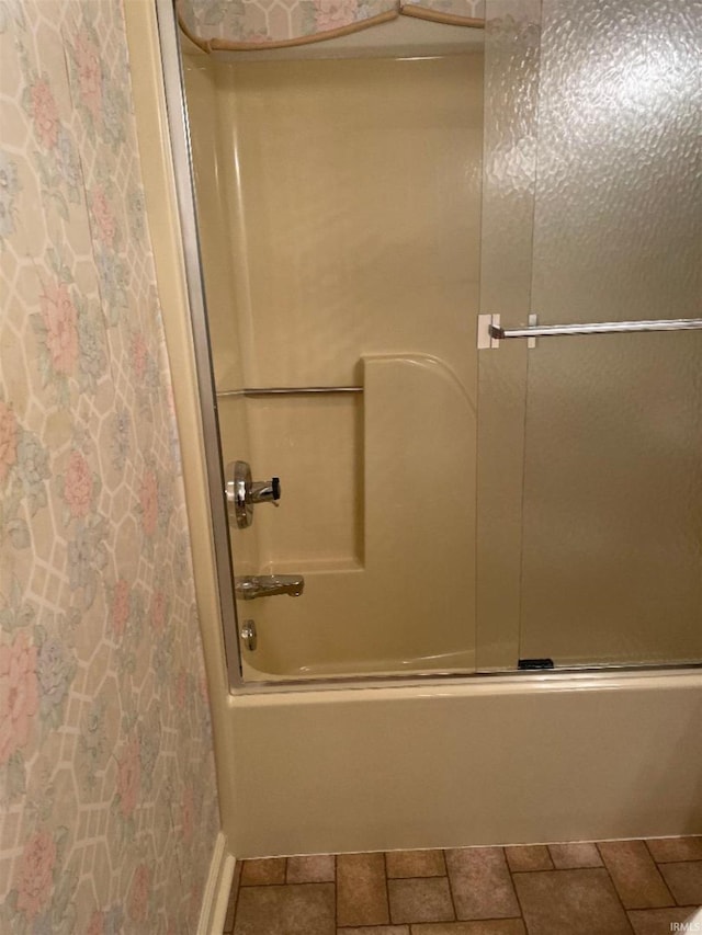 bathroom featuring tile patterned flooring and bath / shower combo with glass door