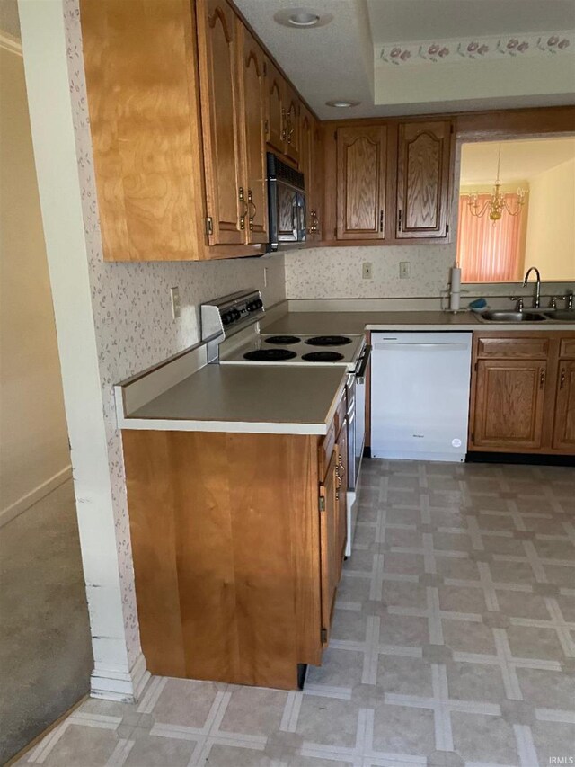 kitchen featuring a chandelier, sink, hanging light fixtures, and white appliances