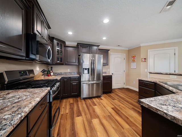 kitchen with crown molding, stainless steel appliances, a textured ceiling, dark brown cabinetry, and light hardwood / wood-style flooring