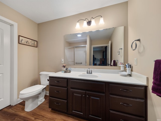 bathroom with wood-type flooring, vanity, a shower with door, and toilet