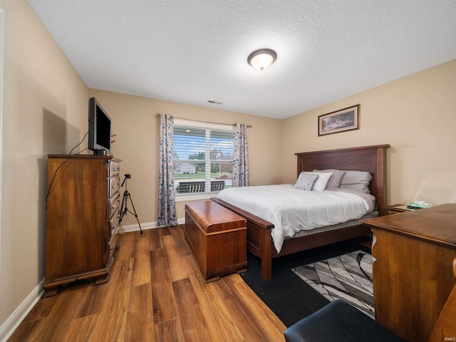 bedroom with a textured ceiling and dark hardwood / wood-style flooring