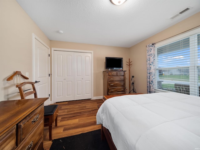 bedroom featuring a closet, a textured ceiling, and dark hardwood / wood-style floors