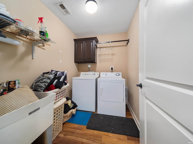 clothes washing area featuring separate washer and dryer, a textured ceiling, cabinets, sink, and dark wood-type flooring