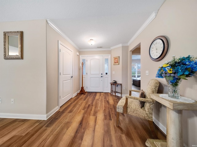 foyer featuring hardwood / wood-style flooring, a textured ceiling, and ornamental molding