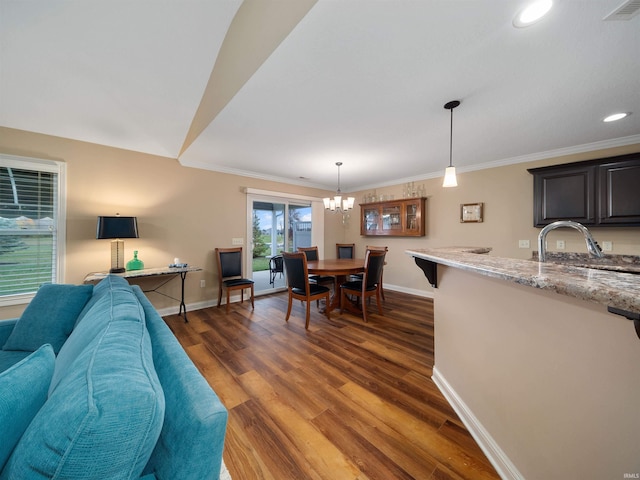 dining area with ornamental molding, dark hardwood / wood-style flooring, a notable chandelier, and sink