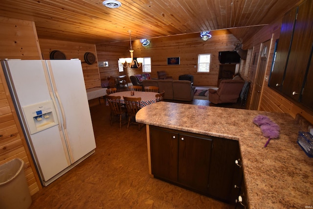 kitchen with white refrigerator with ice dispenser, dark brown cabinets, wood walls, hanging light fixtures, and hardwood / wood-style floors