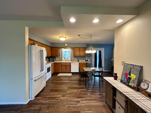 kitchen with dark hardwood / wood-style flooring, a notable chandelier, sink, pendant lighting, and white appliances