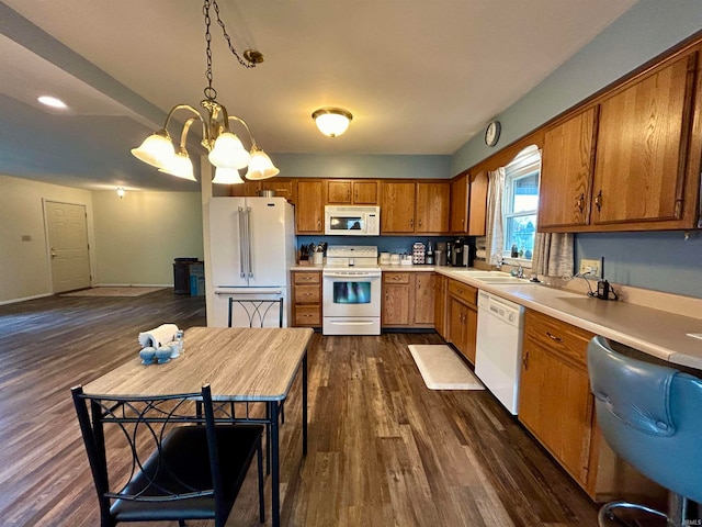 kitchen with an inviting chandelier, sink, dark hardwood / wood-style floors, white appliances, and decorative light fixtures