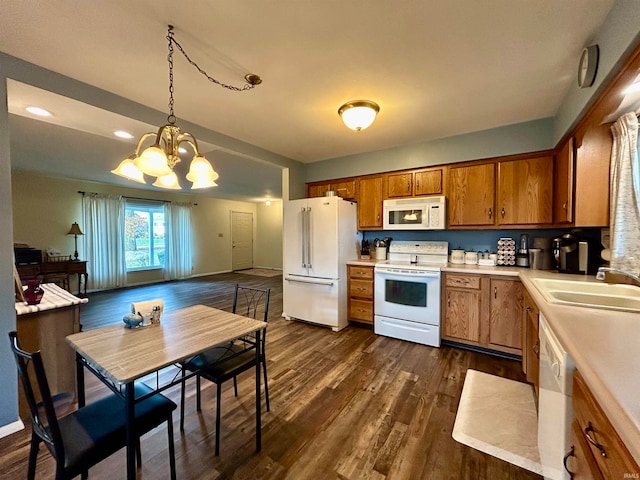 kitchen featuring a notable chandelier, pendant lighting, sink, dark wood-type flooring, and white appliances