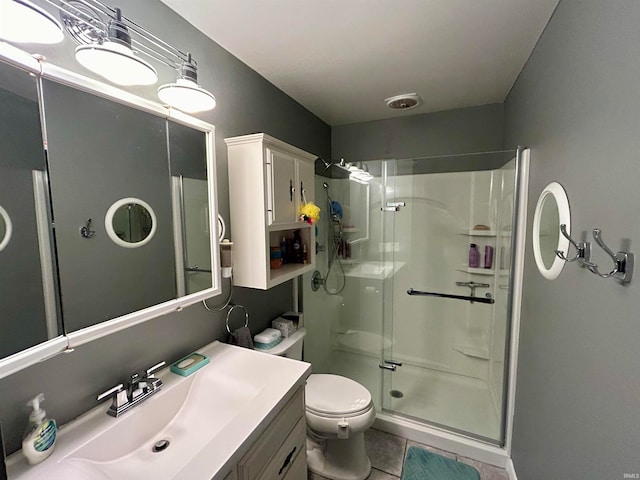 bathroom with tile patterned flooring, vanity, toilet, and a shower with shower door