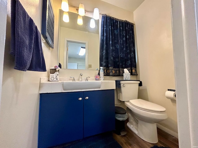 bathroom with toilet, vanity, and wood-type flooring