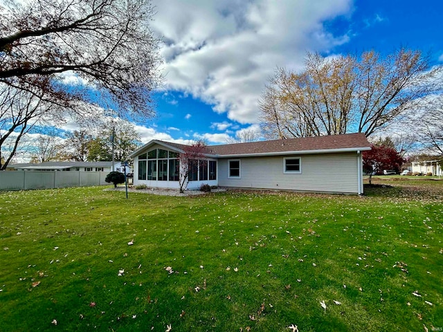 rear view of house with a sunroom and a lawn