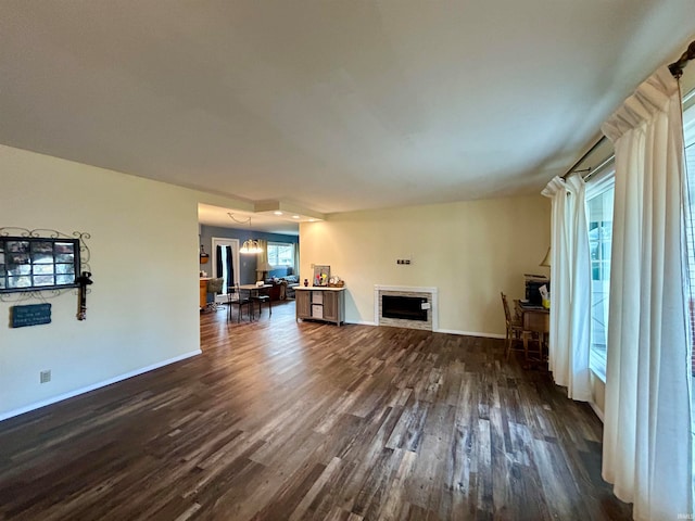 unfurnished living room with a chandelier and dark hardwood / wood-style flooring