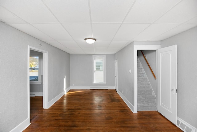 empty room featuring dark wood-type flooring and a drop ceiling