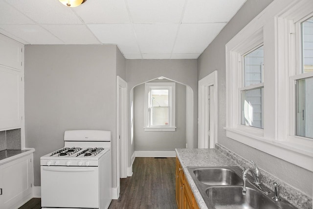 kitchen with gas range gas stove, sink, dark wood-type flooring, and a drop ceiling