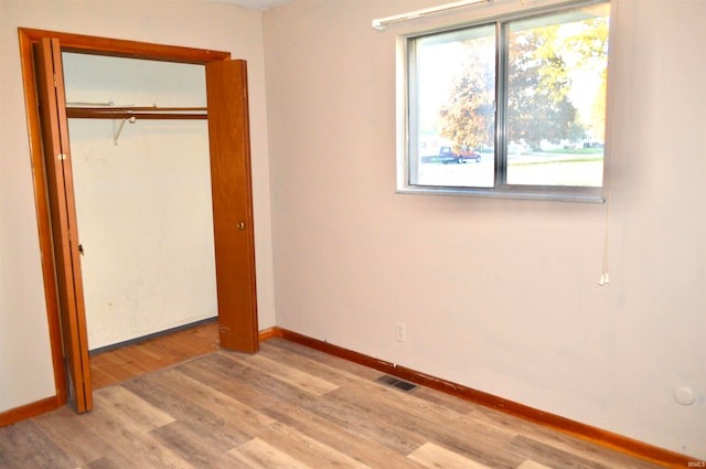 unfurnished bedroom with light hardwood / wood-style flooring and a closet