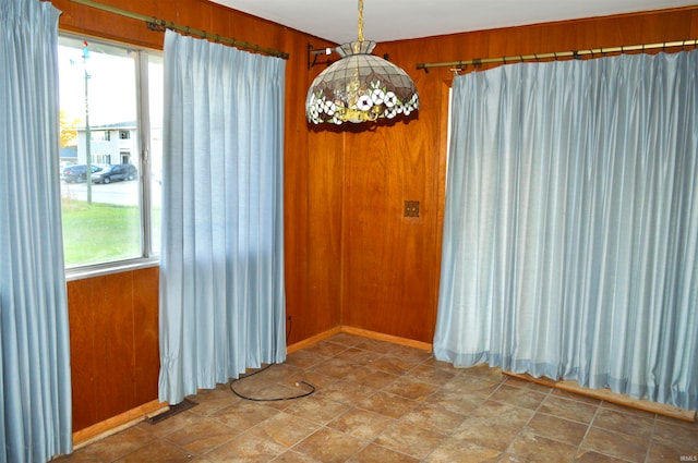 unfurnished room featuring a healthy amount of sunlight and wooden walls