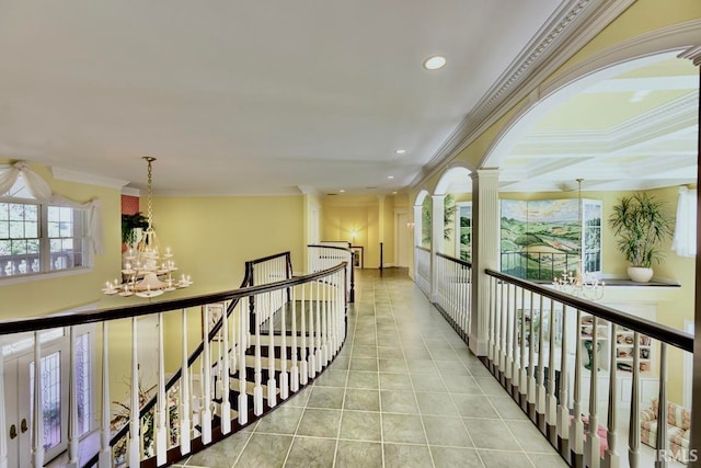 hallway featuring ornamental molding, light tile patterned floors, a chandelier, and ornate columns