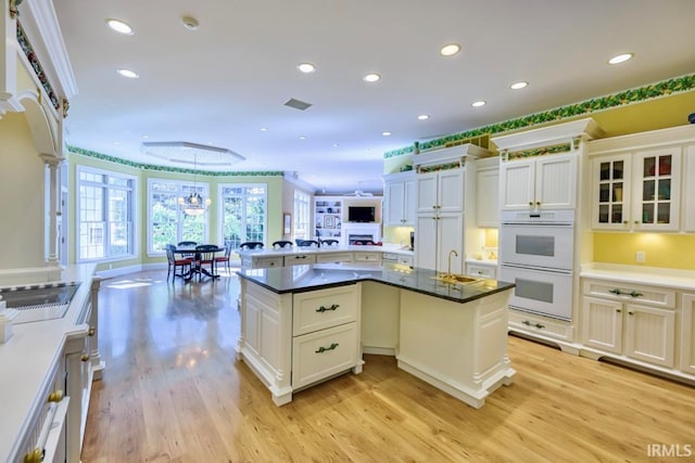 kitchen featuring white cabinets, light wood-type flooring, and double oven