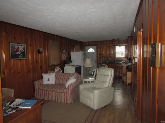 living room with a textured ceiling, wood walls, and dark hardwood / wood-style floors