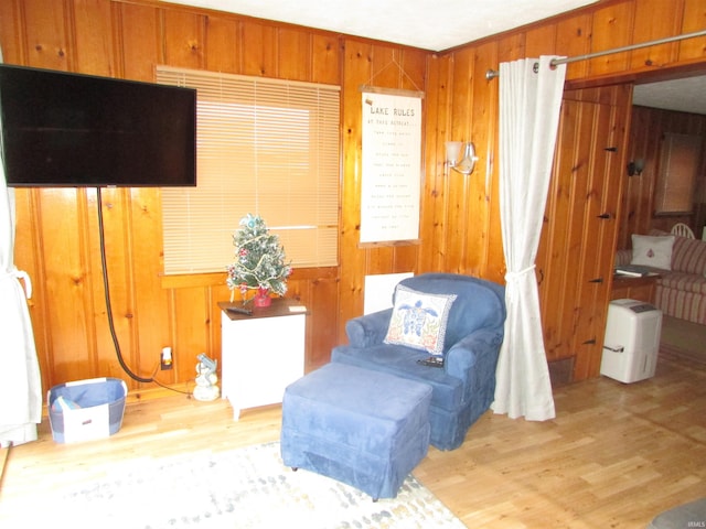 sitting room with light wood-type flooring and wooden walls