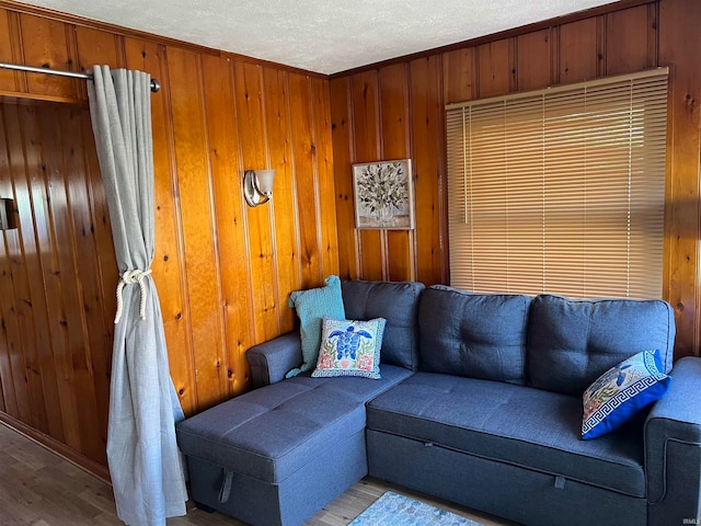 living room with ornamental molding, light hardwood / wood-style flooring, a textured ceiling, and wooden walls