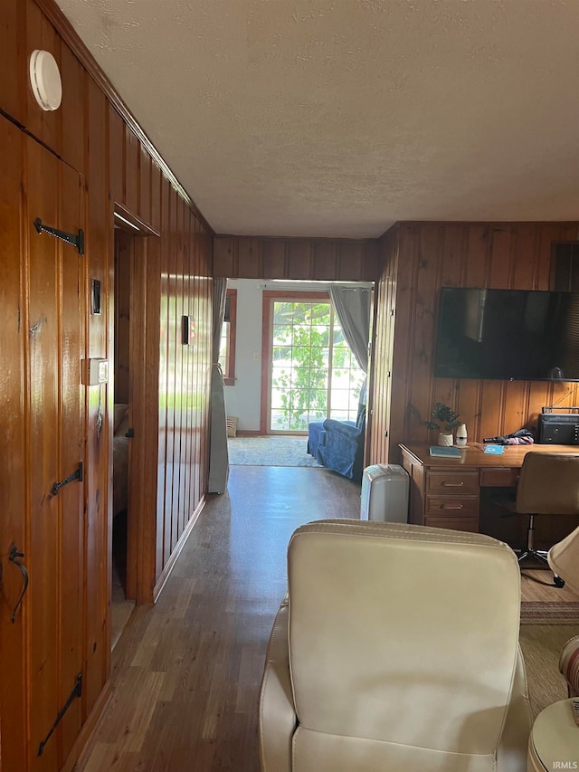 living room featuring a textured ceiling, hardwood / wood-style floors, wooden walls, and built in desk