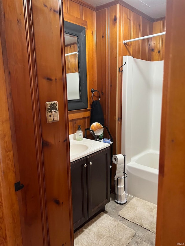 bathroom with shower / bath combination, wood walls, and vanity