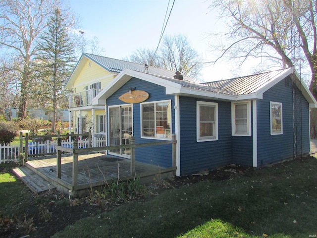 rear view of property with a balcony, a wooden deck, and a yard