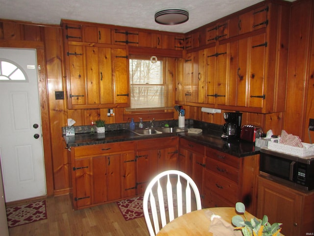 kitchen featuring wood walls, light hardwood / wood-style floors, a textured ceiling, and sink