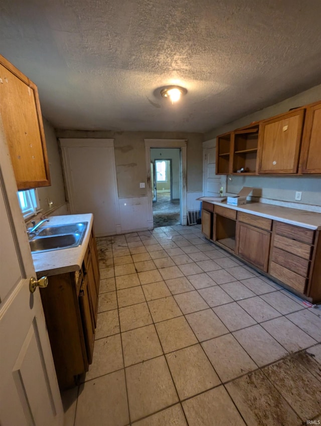 kitchen with a textured ceiling, sink, and light tile patterned floors