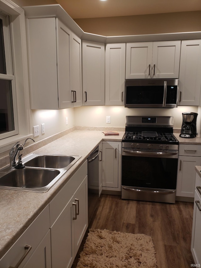 kitchen with stainless steel appliances, white cabinetry, sink, and dark wood-type flooring