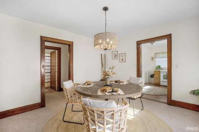 carpeted dining area with an inviting chandelier