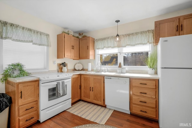 kitchen with white appliances, sink, decorative light fixtures, and light hardwood / wood-style floors