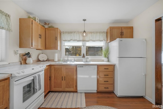 kitchen featuring white appliances, sink, decorative light fixtures, and hardwood / wood-style flooring