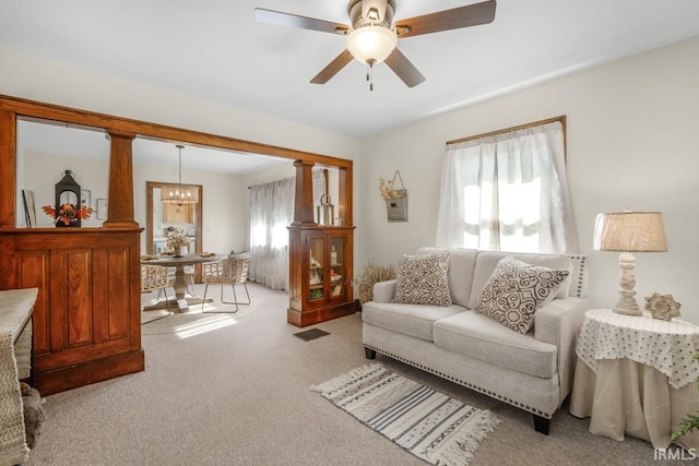 carpeted living room featuring ceiling fan with notable chandelier