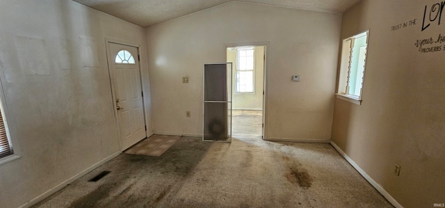 foyer featuring lofted ceiling, a textured ceiling, and carpet flooring