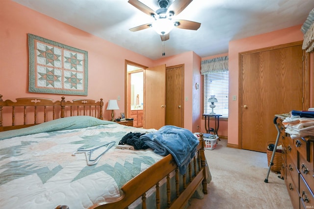 bedroom featuring light colored carpet, ceiling fan, and multiple closets